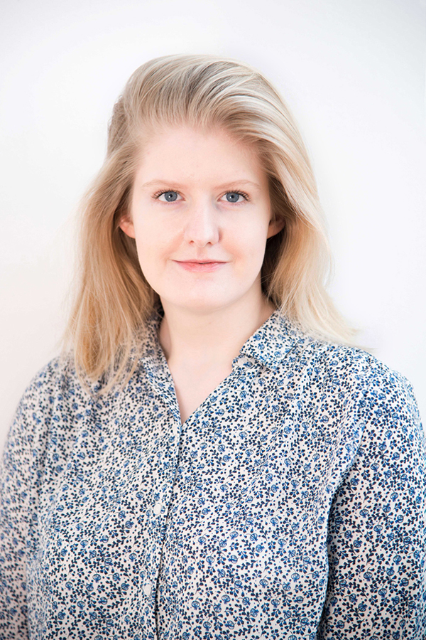 Staff photo of Christina Rupp. She is wearing a floral blouse and standing in front of a white wall.